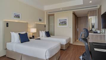 A hotel room with two beds, a desk, a chair, a TV, and a bathroom.