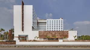 Un hotel moderno con facciata bianca, diversi piani e un mix di elementi in vetro e legno.