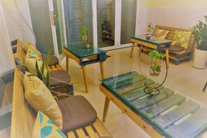 Un salón moderno con una mesa de centro de vidrio, un sofá de madera y una pequeña mesa con una planta.