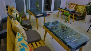 Una sala de estar moderna con una mesa de centro de vidrio, un sofá de madera con cojines y una mesa de comedor de madera con sillas.