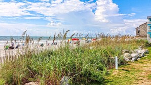 A beach with people, umbrellas, and a building in the background. - Beach House 107 - Two Bedroom, Two Bath Oceanfront Condo (Garden City Beach)