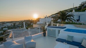 Um terraço no telhado com piscina, espreguiçadeiras e vista para a aldeia lá embaixo.