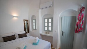 Quarto de hotel com cama, janela, aparelho de ar condicionado e porta.
