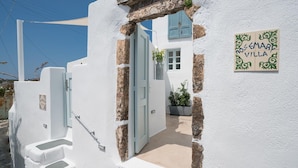 Uma vila branca com uma porta azul, uma escadaria e uma placa com a inscrição 'ROSEMARF VILLA'.