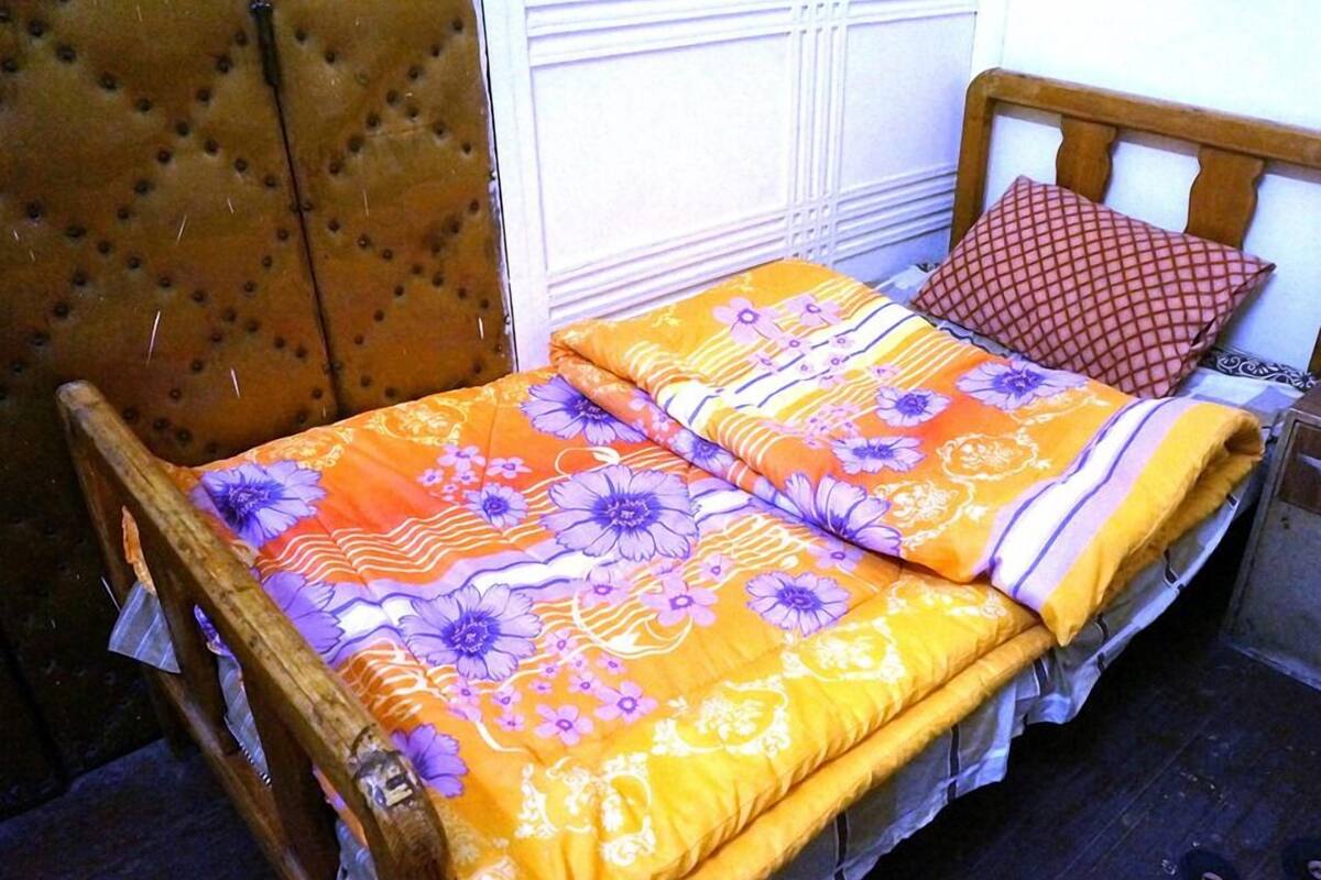 Un lit avec une couvre-lit à motifs floraux, une tête de lit en bois et un coussin à motifs.