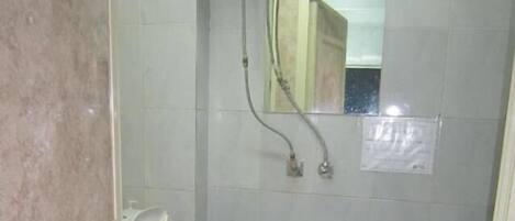 A small bathroom with a toilet, a shower, and a mirror.