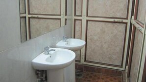 Un baño con dos lavamanos, un espejo y cabina de ducha.