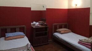 Alojamiento pequeño de una sola habitación con dos camas, un armario de madera y aire acondicionado instalado en la pared.
