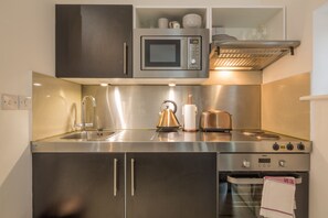 A modern kitchen with stainless steel appliances, including a microwave, toaster, kettle, and oven. - Old Bakery (Cambridge)