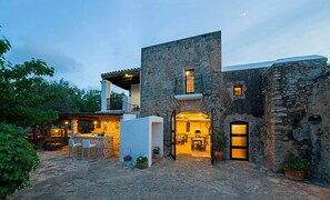 A stone building with a bar area, outdoor seating, and a well-lit entrance. - Hotel Rural Can Partit - Adults Only (Sant Antoni de Portmany)