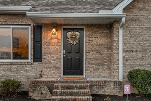 A brick house with a black front door, a wreath, and a sign indicating a retreat. - Rotties' 2 Bedroom Home by RedAwning (Pigeon Forge)