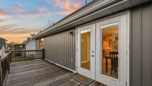A wooden deck with a sliding glass door leading to a dining area with a table and chairs. - Rotties' 2 Bedroom Home by RedAwning (Pigeon Forge)