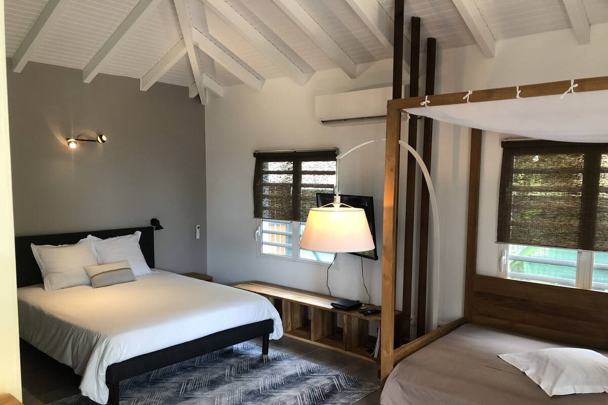 Un dormitorio con cama, mesita de noche, lámpara y ventana con persianas.