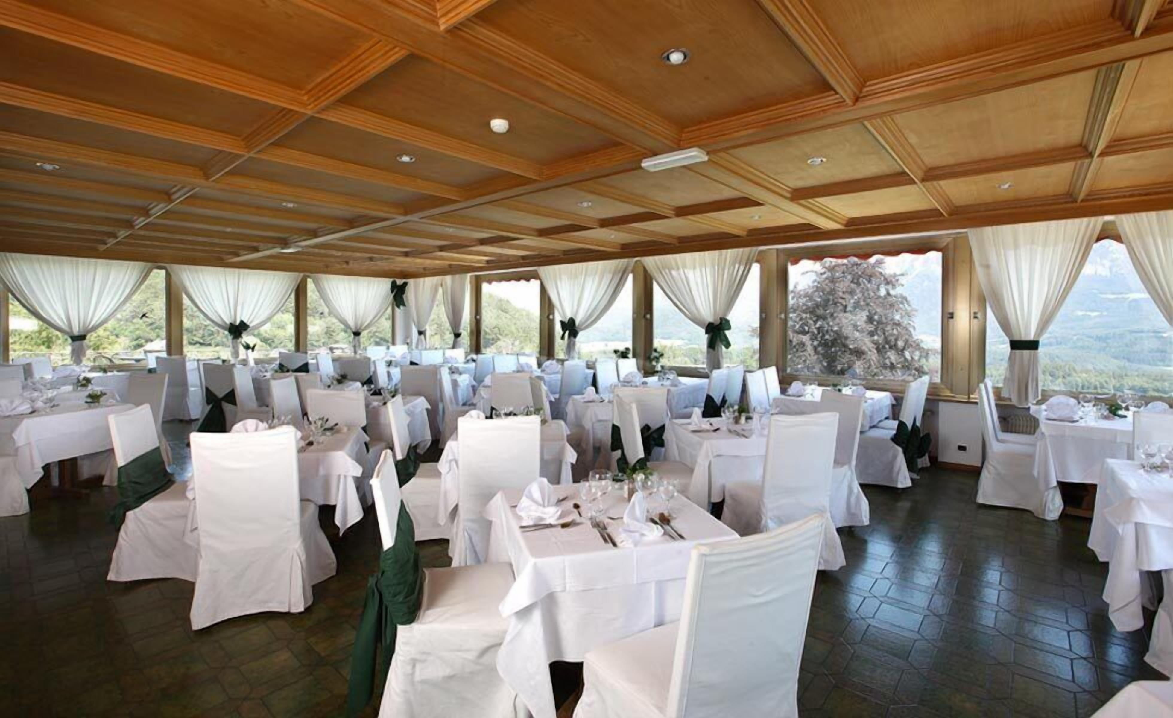 Une salle de banquet avec de nombreuses tables rondes, des nappes blanches et des chaises recouvertes de housses blanches.