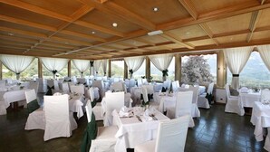 Una sala banchetti con tavoli rotondi, tovaglie bianche e sedie con coperture bianche.
