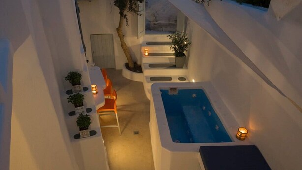 Un espace extérieur moderne et minimaliste, doté d’un jacuzzi, d’un coin salon et de plantes en pot.