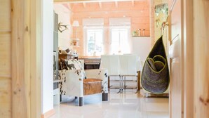 Une cuisine moderne avec des meubles blancs, une table à manger en bois et un fauteuil suspendu orné d’une pancarte sur laquelle est écrit « BIENVENUE ».