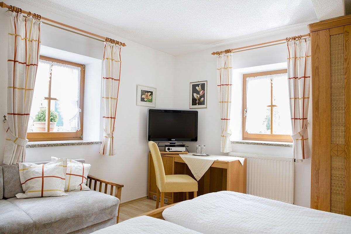 Un dormitorio con dos camas, un escritorio con computadora, un televisor y una silla.