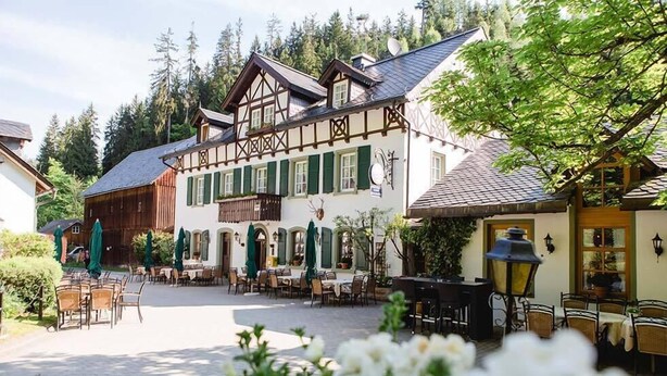 Un bâtiment de style européen traditionnel, doté d’une cour intérieure, de sièges en plein air et offrant une vue sur les montagnes.