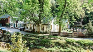 Un jardin paisible avec un belvédère, un petit bâtiment blanc et un mur de pierre.