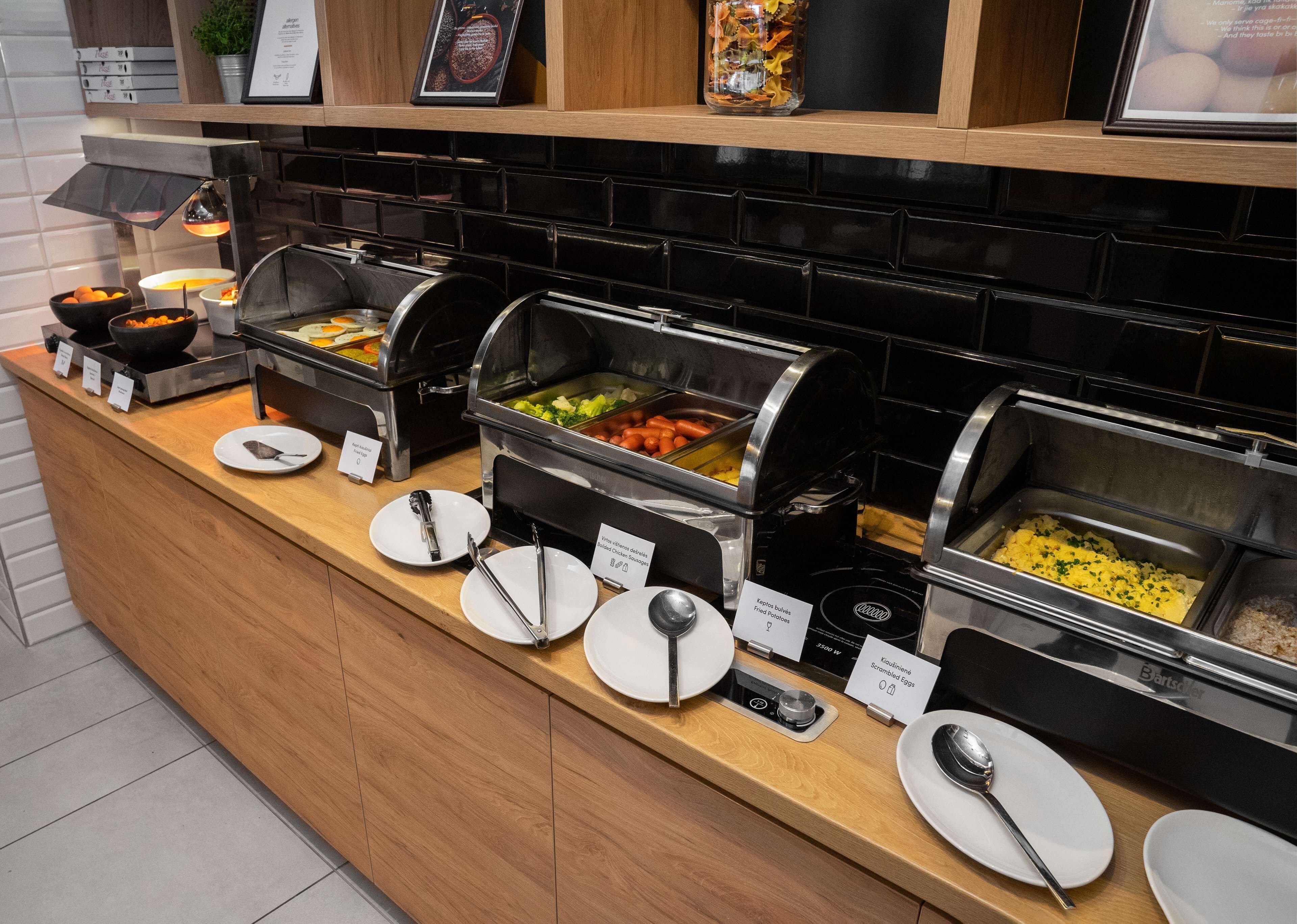 Un buffet con diverse opzioni gastronomiche, tra cui uova strapazzate, patate fritte e verdure.