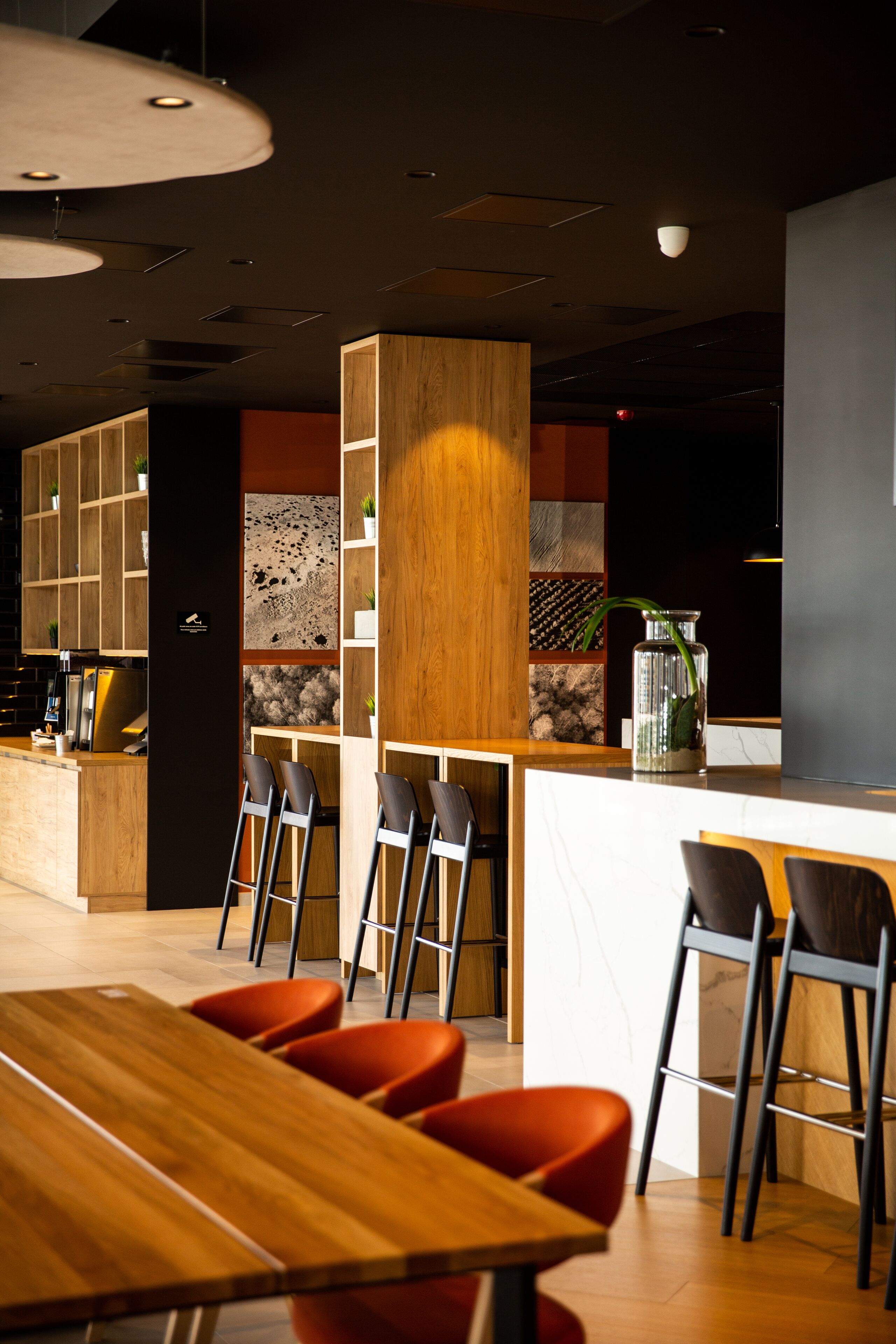 A modern restaurant interior with wooden furniture, a bar area, and a seating arrangement.