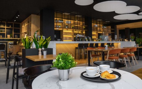 A modern cafe with a marble table, a small potted plant, a cup of coffee, and a plate of pastries.