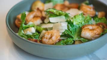 A bowl of salad with shrimp, lettuce, and cheese.