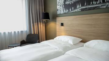 A hotel room with a bed, a chair, a lamp, and a wall-mounted light fixture.