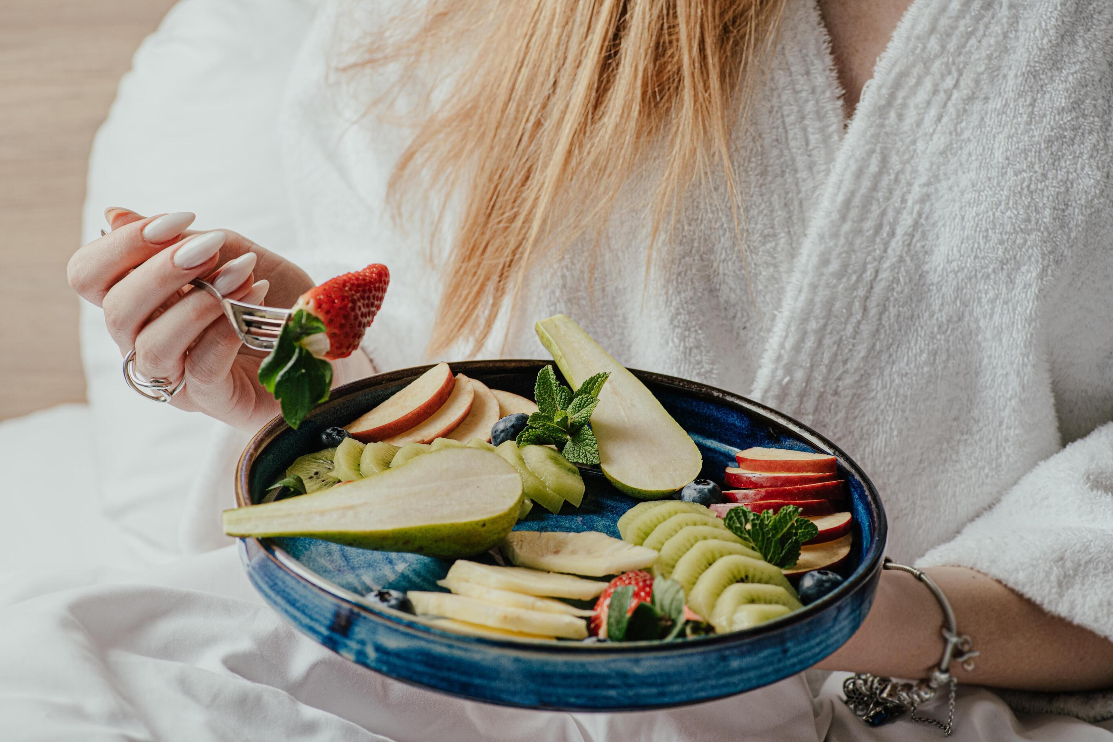 Una persona sosteniendo un tazón de ensalada de frutas.