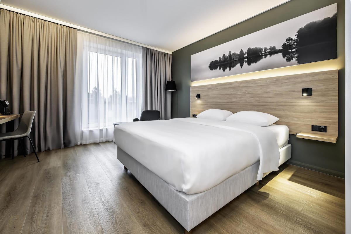 A modern hotel room with a large bed, a desk, and a chair.