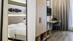A hotel room with a bed, a desk, a chair, and a large window with curtains. - Park Inn by Radisson Vilnius Airport Hotel & Conference Centre (Vilnius)