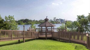 A gazebo with a wooden roof and railings, surrounded by a grassy area and a body of water in the background. - 2 BR RESORT IN PERFECT LOCATION NEAR UNIVERSAL (Orlando)