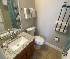 Un baño con lavamanos de granito, un inodoro y un perchero para toallas.