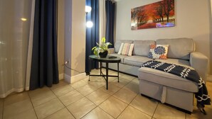 A living room with a sofa, a coffee table, a potted plant, and a painting on the wall. - 2 BR RESORT IN PERFECT LOCATION NEAR UNIVERSAL (Orlando)