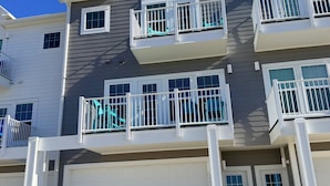 Un edificio residencial de varios pisos con garaje, balcones y un cielo azul despejado.