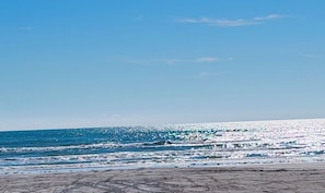 A beach with waves and a clear sky.