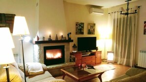 Una sala de estar con chimenea, sofá, mesa de centro y televisor.
