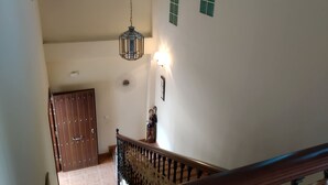 Una escalera con barandilla de madera y un colgador con luz.