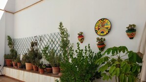 Una terraza con plantas en macetas, un muro decorativo y una valla de celosía.