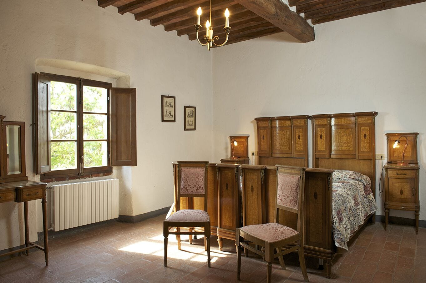 A bedroom with a wooden bed, two chairs, a dresser, and a window with shutters.