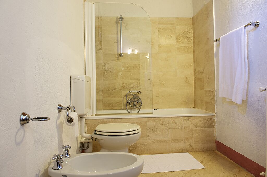 A bathroom with a glass-enclosed shower, a bathtub, a toilet, and a sink.