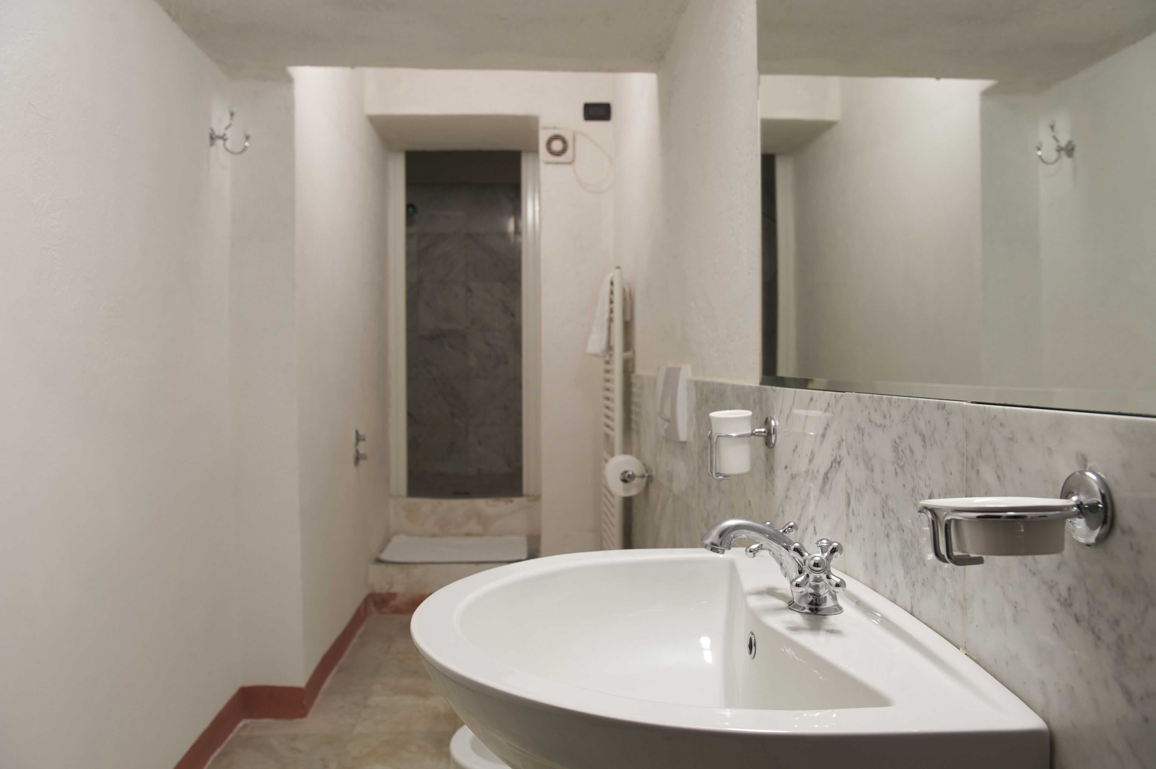 Un bagno con un lavandino bianco, uno specchio e uno spazio doccia.