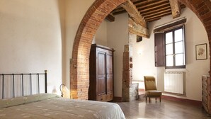 A bedroom with a bed, a chair, a wardrobe, and a window. - Castello di Modanella (Rapolano Terme)