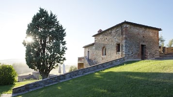A stone building with a sloped roof, a staircase leading to the entrance, and a tree in the foreground.