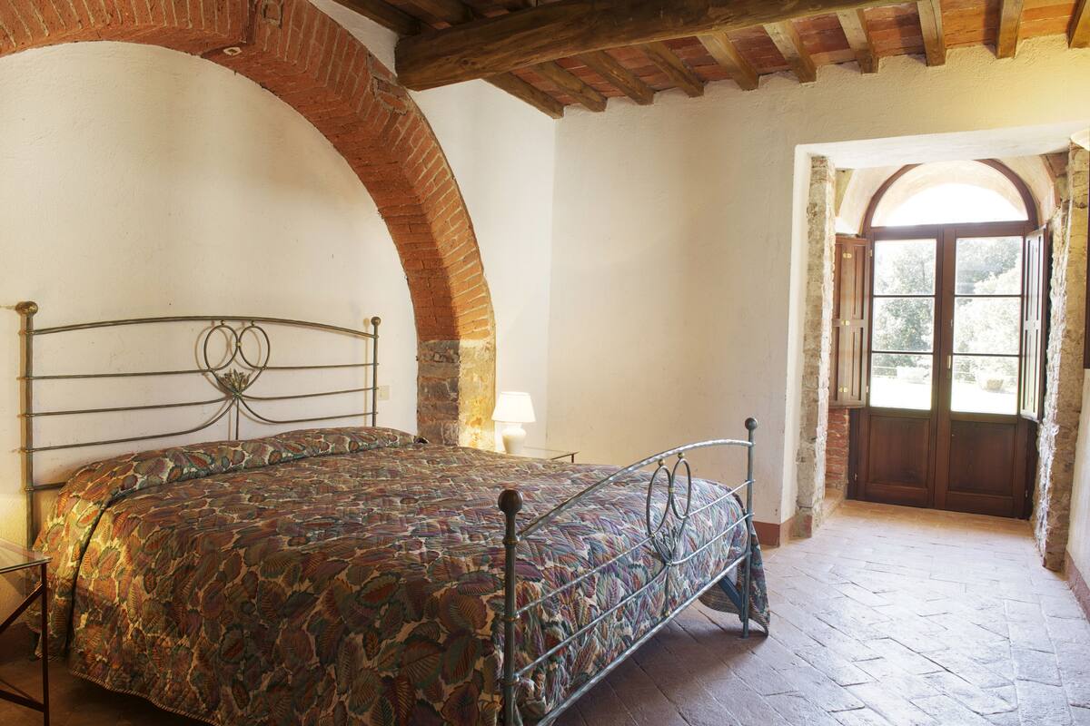 A bedroom with a bed, a stone wall, and a wooden door.