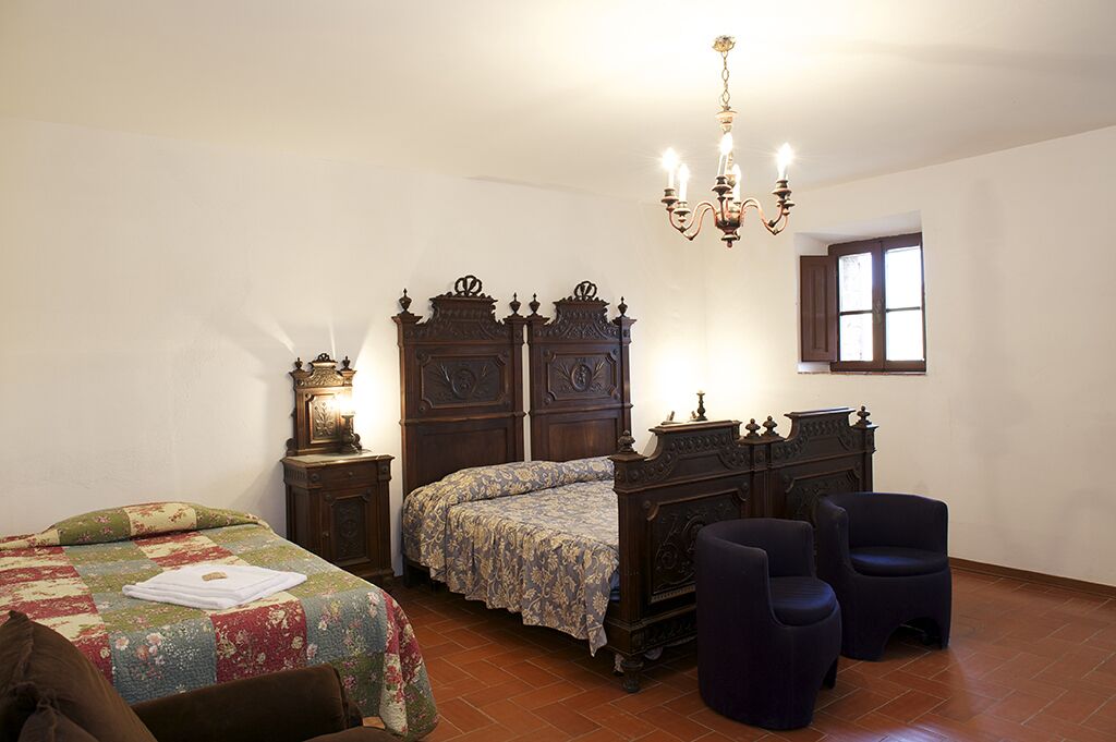 A bedroom with a wooden bed, a nightstand, a dresser, and two chairs.