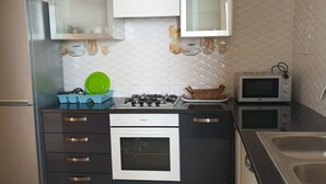 Eine kleine Küche mit Gasherd, Backofen, Mikrowelle und Spüle.