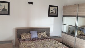 Ein Schlafzimmer mit einem Bett, einem Kleiderschrank und zwei gerahmten Bildern an der Wand.