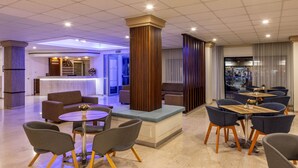 A modern hotel lobby with a reception desk, seating area, and a bar. - Seagull Hotel Apartments (Paralimni)
